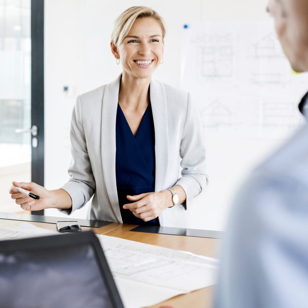 Smiling businessman sitting in hammock, using laptop