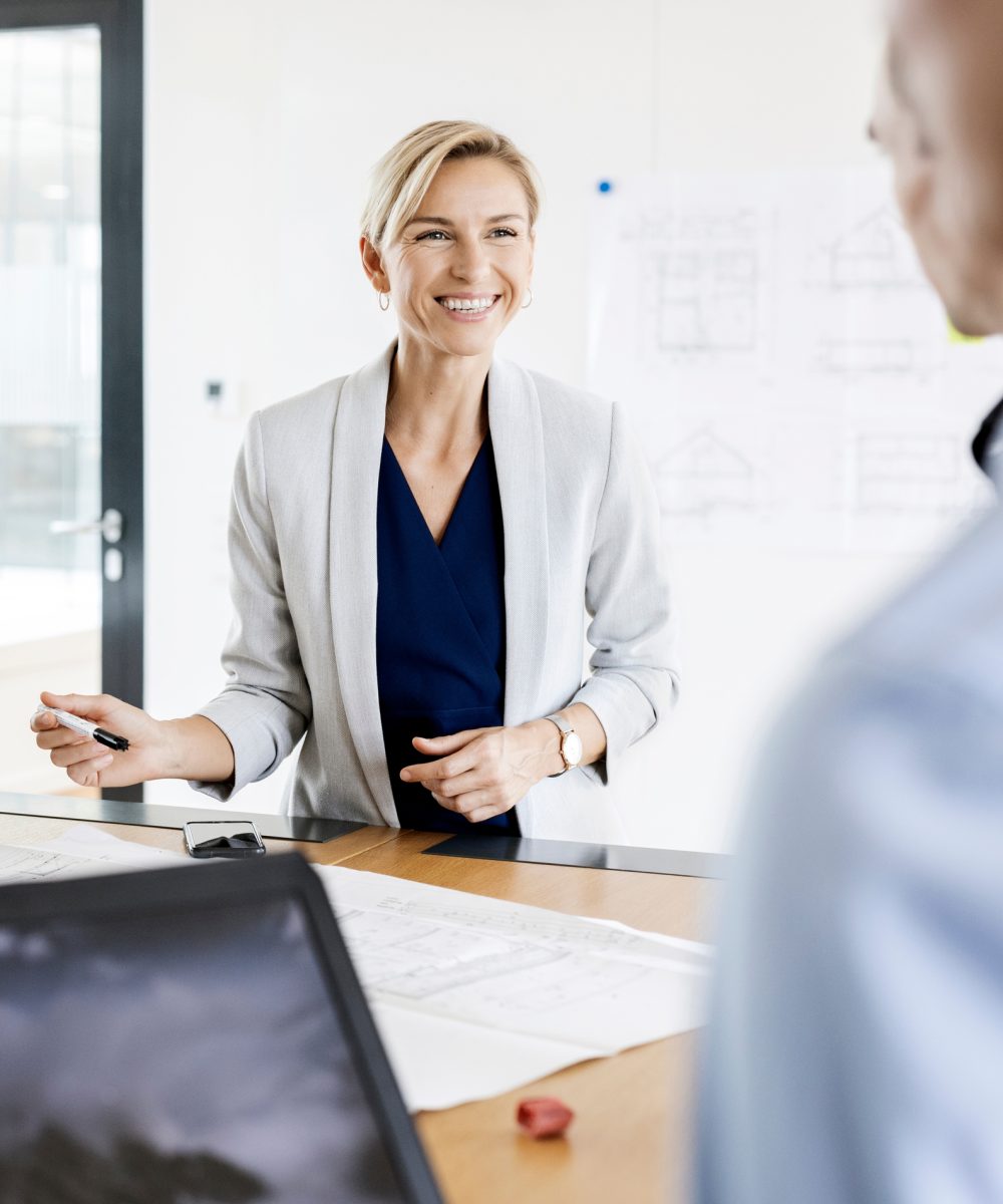 Smiling businessman sitting in hammock, using laptop